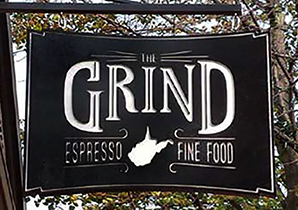 Black sign with white letters that says Grind WV Espresso Fine Food with the shape of WV